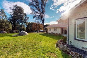 A residential property with a well-maintained lawn, large rocks, and a house with a visible front door and windows. - Bear Den - Near Yosemite & Bass Lake, Deck (Oakhurst)