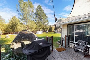 Eine Terrasse mit Grill, Sitzbank und einem großen Felsen.