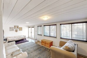 A spacious room with a bed, a sofa, a wooden chest, and large windows. - Bear Den - Near Yosemite & Bass Lake, Deck (Oakhurst)