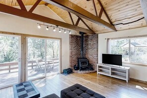 A spacious living area with a fireplace, a television on a stand, and a large sliding glass door leading to an outdoor deck.