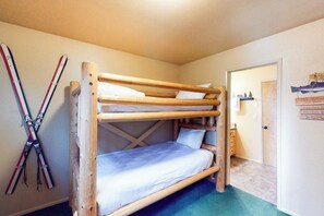 Ein Schlafraum mit Etagenbetten und Ski, die an der Wand lehnen.