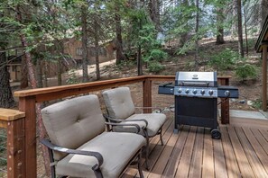 Eine Terrasse mit Grill und zwei Stühlen.