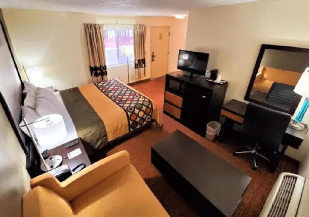 A hotel room with a bed, a desk, a chair, a television, and a window with curtains.