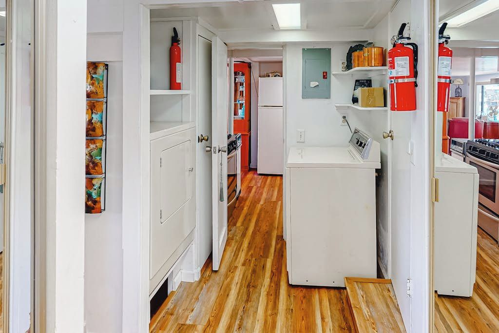 A narrow hallway with white cabinets, a refrigerator, and a fire extinguisher.