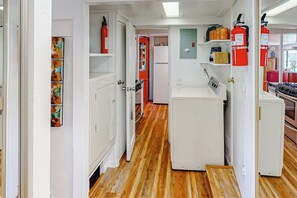 Ein schmaler Flur mit weißen Schränken, einem Kühlschrank und einem Feuerlöscher.