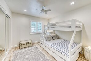 A bunk bed room with a ceiling fan, a window, a suitcase, and a radiator. - Slide Creek Retreat - Pool, Hot Tub, Walk to Lake (Bass Lake)
