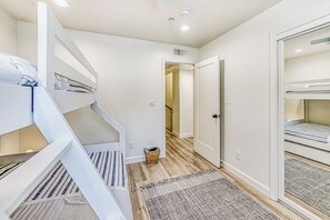 Ett sovrum med våningssängar, en trappa, en garderob och en hall som leder till ett annat rum.