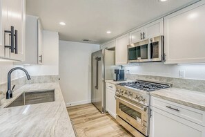 A modern kitchen with stainless steel appliances, a gas stove, a built-in oven, and a microwave. - Slide Creek Retreat - Pool, Hot Tub, Walk to Lake (Bass Lake)