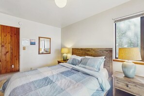 A bedroom with a bed, a wooden headboard, a window with a view, and a nightstand with a lamp. - Vernal Vista - Inside Yosemite, Deck & Views (Yosemite West)