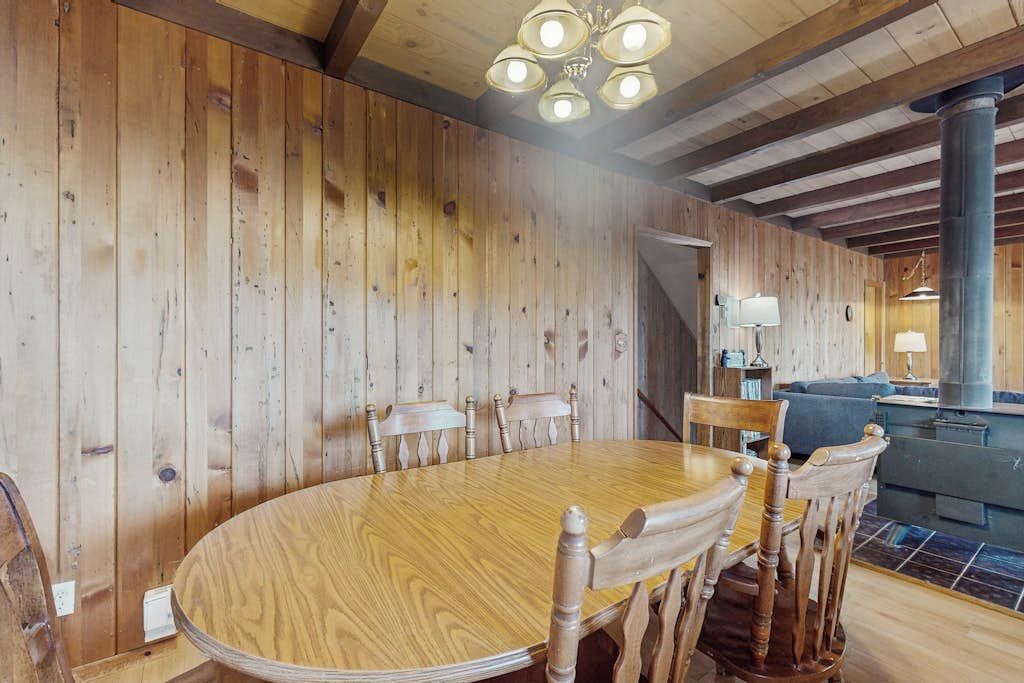 Interior de madera con una mesa redonda y sillas para comer, una escalera y una chimenea.