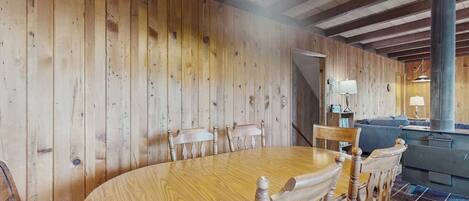 Interior de madera con una mesa redonda y sillas para comer, una escalera y una chimenea.