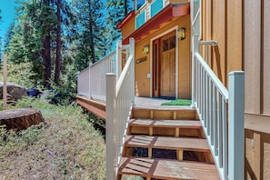 A wooden deck leading to a building with a wooden door and a small porch area.