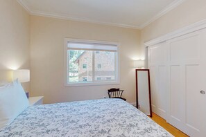 A bedroom with a bed, a chair, a window, and a door.