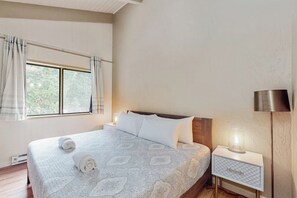 A neatly made bed with a patterned bedspread, a bedside lamp, and a window with curtains. - Snowy Pines - Near Yosemite, Wood Fireplace (Fish Camp)