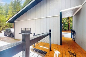 Un espace extérieur abrité doté d’une terrasse en bois, d’une rambarde en métal et d’un véhicule garé à l’extérieur.
