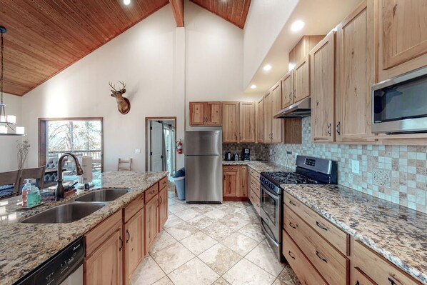 A kitchen with wooden cabinets, granite countertops, a stainless steel refrigerator, and a microwave.