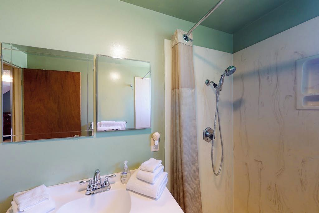Une salle de bain avec un lavabo, un miroir et une douche.