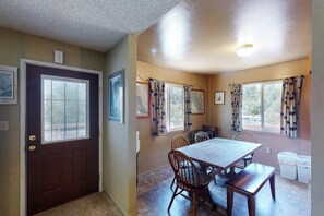 A dining area with a table and chairs, a door with a window, and a ceiling light. - Hodges Hill Yosemite House (Oakhurst)