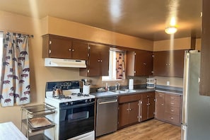 A compact kitchen with a stove, sink, and refrigerator. - Hodges Hill Yosemite House (Oakhurst)