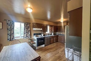 A kitchen with wooden cabinets, a stove, and a refrigerator. - Hodges Hill Yosemite House (Oakhurst)