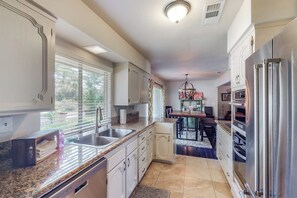 A kitchen with granite countertops, stainless steel appliances, and a dining area with a chandelier. - Putney Place - Hot Tub & Mountain Views (North Fork)