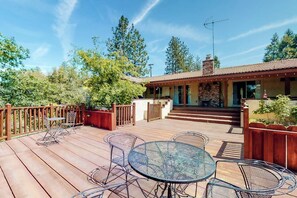 A wooden deck with outdoor furniture, a covered patio area, and a brick building with a chimney. - Putney Place - Hot Tub & Mountain Views (North Fork)