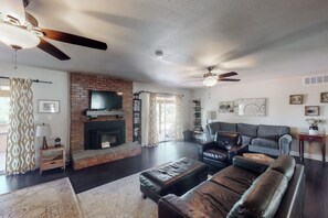 A living room with a fireplace, leather sofas, and a ceiling fan. - Putney Place - Hot Tub & Mountain Views (North Fork)
