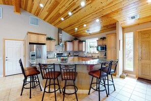 A kitchen with a central island, bar stools, wooden cabinets, stainless steel appliances, and a wooden ceiling. - Murray Lake Retreat - Near Bass Lake, Fireplace (Bass Lake)
