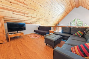 A cozy living room with a wooden ceiling, a flat-screen TV, a sofa, and a coffee table. - Oso Lodge - Ping-Pong, Deck & EV Charger (Yosemite West)