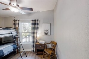 A bedroom with a bunk bed, a desk with a lamp, a chair, a ceiling fan, and a window with curtains. - Out in the Wild - Near Bass Lake & Dog-Friendly (Oakhurst)