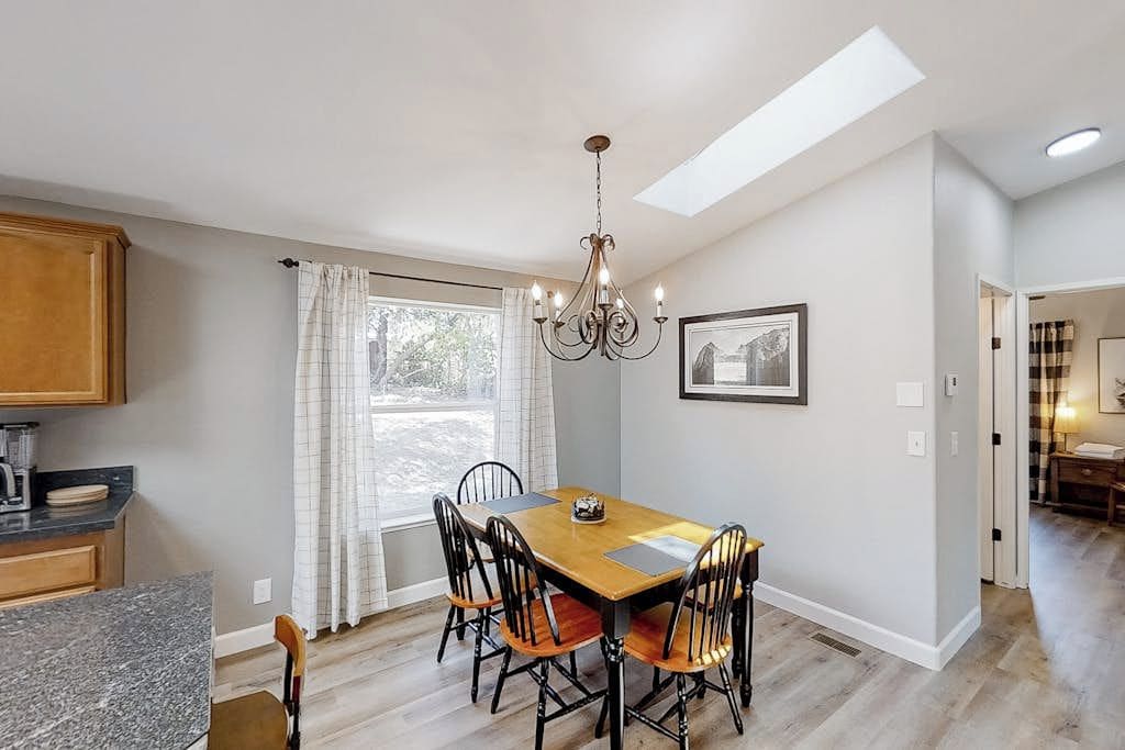 A dining area with a table, chairs, and a chandelier.
