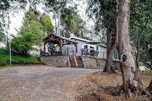 A building with a stone foundation, a wooden deck, and a staircase leading to a porch. - Out in the Wild - Near Bass Lake & Dog-Friendly (Oakhurst)