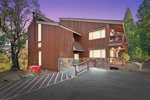 A two-story wooden building with a balcony, a stone entrance, and a red fire hydrant.