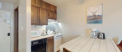 A kitchen with wooden cabinets, a stove, a dishwasher, and a dining table with chairs.