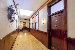A hotel hallway with wooden floors, a skylight, and a door marked with the number 2. - 1BR I Roberts Loft #2, Walk to DT, Queen, W/D (Fargo)