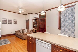 A kitchen with wooden cabinets, a dishwasher, a dining table, and a ceiling fan. - 1BR I Roberts Loft #2, Walk to DT, Queen, W/D (Fargo)