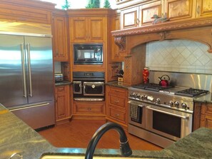 A kitchen with wooden cabinets, stainless steel appliances, and a tiled backsplash. - Knott Lakeview - Lake Views, Boat Slip & Dogs OK (Bass Lake)