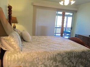 A bedroom with a bed, a nightstand, a lamp, a window with a view of a balcony, and a door. - Knott Lakeview - Lake Views, Boat Slip & Dogs OK (Bass Lake)