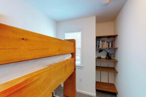 Ein Zimmer mit einem Holzbett, einem Bücherregal und einem Fenster mit Jalousien.