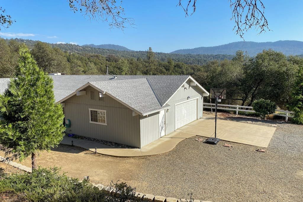 A single-story building with a garage, surrounded by a gravel driveway and a white fence.