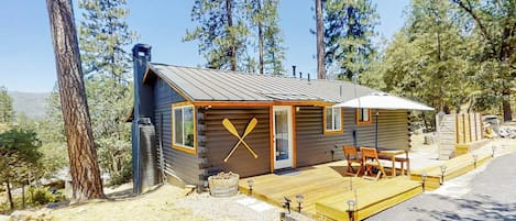 A cabin with a deck, outdoor seating, and a chimney.