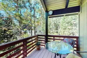 A covered outdoor area with a glass table and chairs, surrounded by a wooden deck and a railing. - Wishing Well Cabin - Near Yosemite & Bass Lake (Bass Lake)
