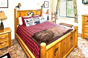 A wooden bed with a red and black checkered bedspread, two bedside lamps, and a wooden nightstand with drawers. - Wishing Well Cabin - Near Yosemite & Bass Lake (Bass Lake)