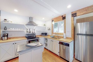 A modern kitchen with white cabinetry, stainless steel appliances, and a wooden accent wall. - Starfall - Modern Yosemite Home, Great Deck (Yosemite West)