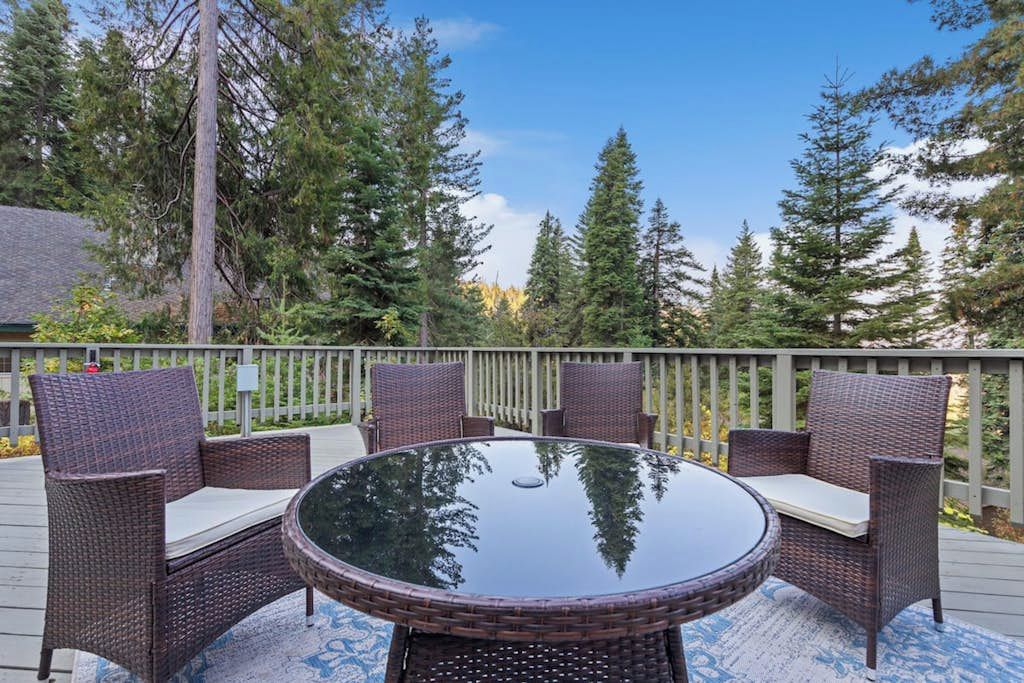 An outdoor patio with a round glass table surrounded by wicker chairs.