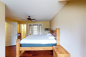 Ein Schlafzimmer mit einem hölzernen Bett, einem Deckenventilator und einer Tür zu einem weiteren Raum.