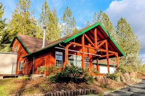 A wooden cabin with a green roof and a porch, surrounded by trees. - Calandri Lakeview House (Bass Lake)