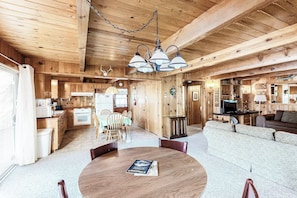 A wooden interior with a dining table, chairs, a sofa, and a kitchen area. - Lancaster Cabin - Bass Lake, Fireplace & Deck (Bass Lake)