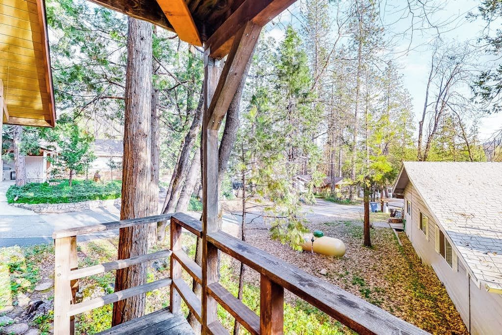 A wooden deck with a railing overlooking a residential area with houses and trees.