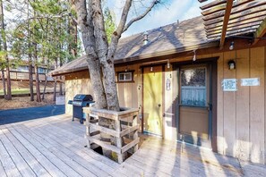 A wooden cabin with a deck, a grill, and a door with a sign. - Lancaster Cabin - Bass Lake, Fireplace & Deck (Bass Lake)